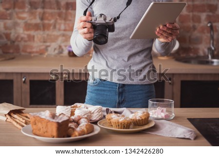 Food photographer. Blogging business. Man with tablet and camera. Cakes and pastries assortment around.
