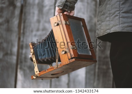 Photographer holds vintage large format studio camera, 5x7 inches. Concept - photography of the 1930s-1950s.