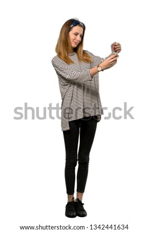 A full-length shot of a Young woman with headscarf making a selfie over isolated white background