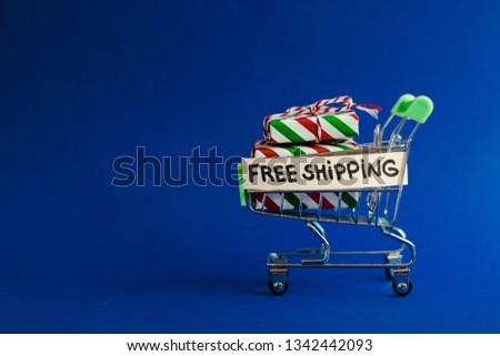 Free shipping concept, shopping cart with gifts, parcels in it on blue background