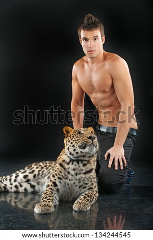 Portrait of young man with leopard, isolated on black background.