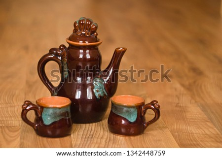 Ceramic teapot and cups on wooden flow