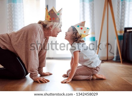 A portrait of small girl with grandmother having fun at home. Royalty-Free Stock Photo #1342458029