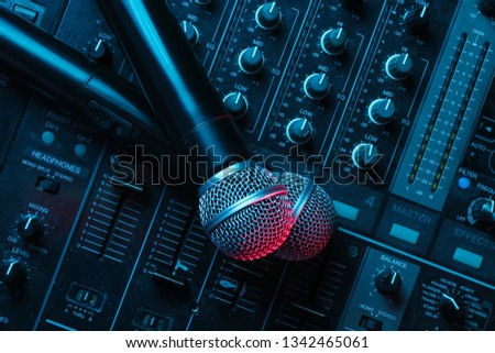 Night club, nightlife concept. Disco. Two microphone on DJ remote. Neon red blue light
