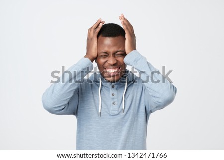 African american man feeling severe headache. He is suffering, holding his head with both hands. studio shoot