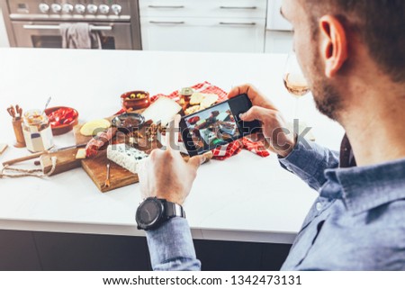 camera eats first concept: man taking pictures with his phone of the food on the table. social media life concept