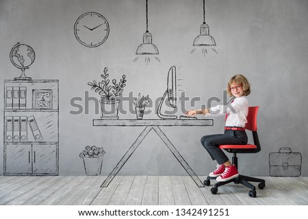 Happy child sitting at the desk in imaginary office. Business or education concept Royalty-Free Stock Photo #1342491251