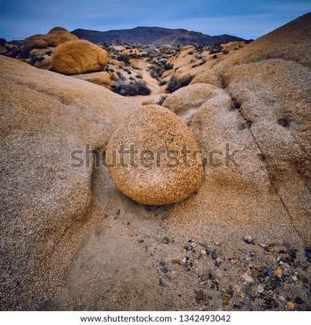 Boulder in a wash with Pinto Mountains in the background at Joshua Tree National Park.