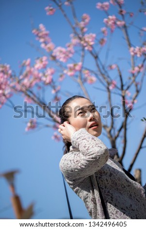 Pretty woman with pink sakura flower and blue sky background.