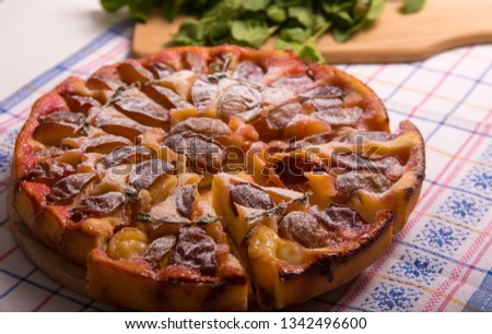Food. Sweet pastries. Round cake with plums and thyme. Pictured with mint, wooden board and knife