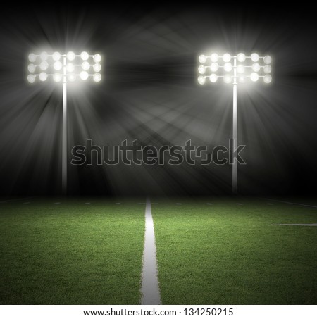 Two Stadium football game lights are shinning on a green grass field for a sport concept. Royalty-Free Stock Photo #134250215