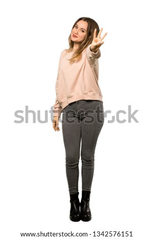 A full-length shot of a Teenager girl with pink sweater happy and counting three with fingers over isolated white background