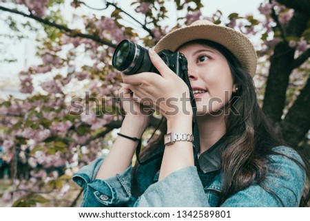 Happy young woman traveling with beautiful pink Cherry Blossom in japan mint in spring season. landmarks and popular for tourist attractions osaka. girl hold professional camera take photo of sakura