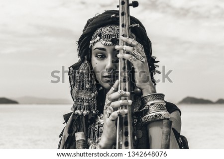 Beautiful young stylish tribal woman in oriental costume playing sitar outdoors. Close up Royalty-Free Stock Photo #1342648076