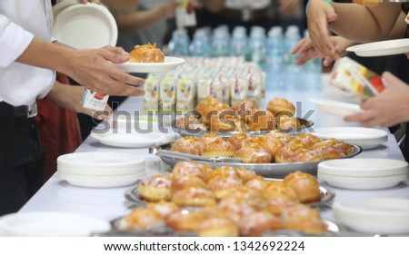 The people are enjoy buffet by picking the Pilish's dessert which called paczki with blurred foreground.