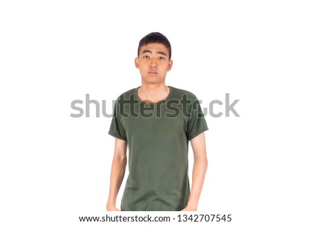 The  young Thai man in short hair style with olive green shirt stands showing his  bored face