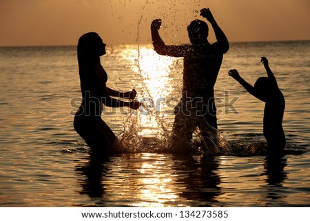 Silhouette Of Family Having Fun In Sea On Beach Holiday