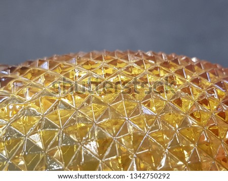 transparent yellow glass with geometric shapes of rhombuses. isolated gray background