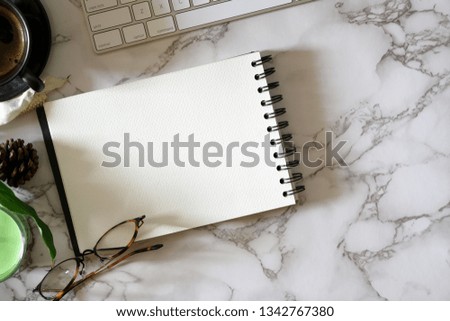 Open blank notebook on marble top table with office supplies