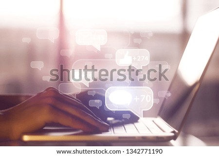 Side view of hands using laptop with communication icons on blurry background. Social network and website concept. Double exposure 