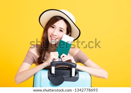 happy tourist woman in summer hat holding  passport and suitcase