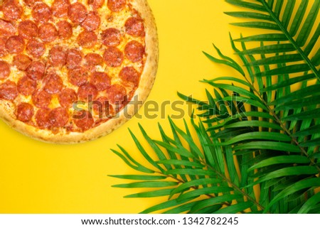 Pizza flat lay summer vacation decoration tropical palm leaves on pastel yellow background. Summer concept.