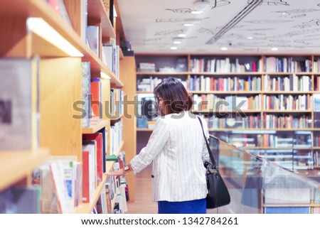 Woman is finding and reading a book in the bookstore.