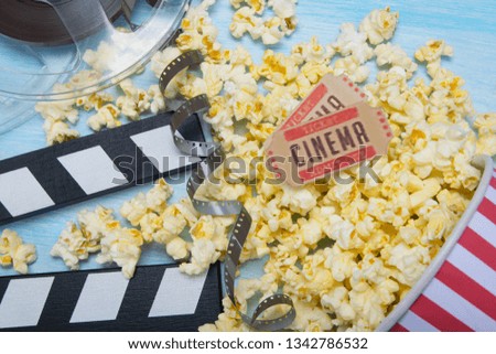 on a light background, a bucket with scattered popcorn, film, two movie tickets and a double for filming