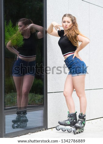 Happy joyful young woman wearing roller skates riding in town. Female being sporty having fun during summer time.