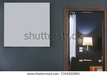 Blank frame on grey wall in Modern interior with open door to bed room