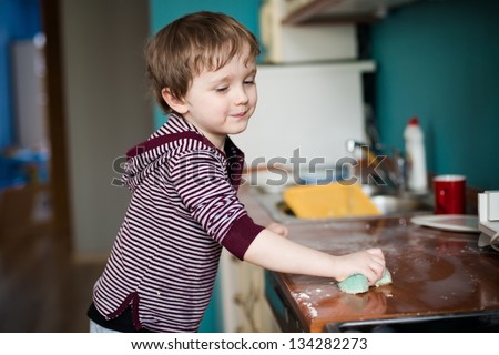 Boy cleaning the kitchen after making dinner Royalty-Free Stock Photo #134282273