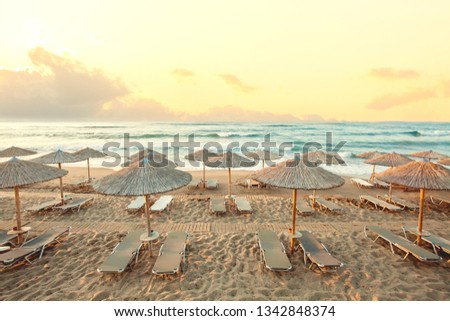 Morning beach, umbrellas, sunbeds and dawn sky. Summer holiday concept
