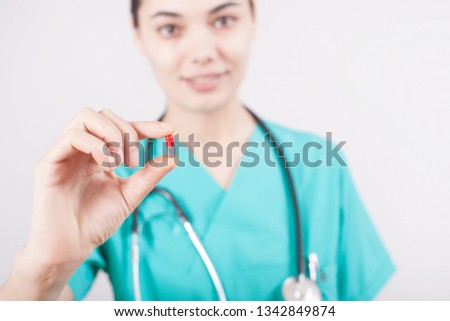 Young doctor hand holding pill on gray background