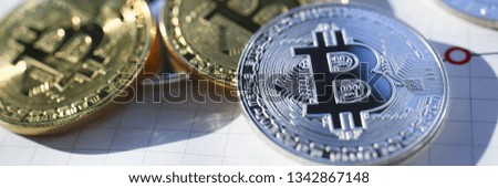 Silver and golden bitcoin on paper graph background