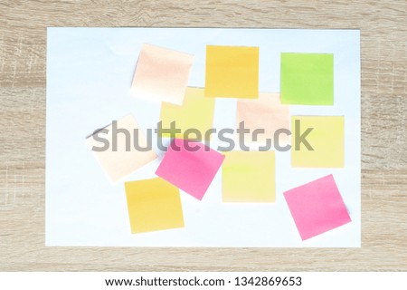 colorful stickers on a white A4 sheet on a wooden background