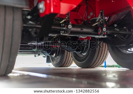 Underneath a New Semi Truck Trailer showing the rear Chassis and Three axles and Wheels with Tyre Treads and Airlines. Royalty-Free Stock Photo #1342882556