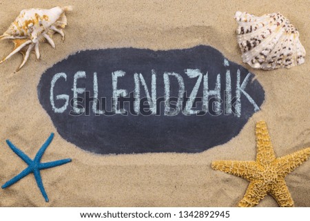 Handwritten word GELENDZHIK written in chalk, among seashells and starfishes. Top view