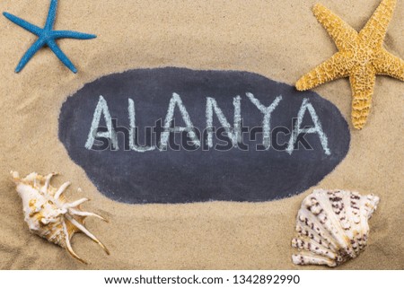 Handwritten word ALANYA written in chalk, among seashells and starfishes. Top view
