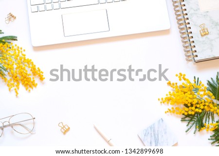 Business concept spring flat lay with a computer and fresh flowers on the white background. Top view. Copy space