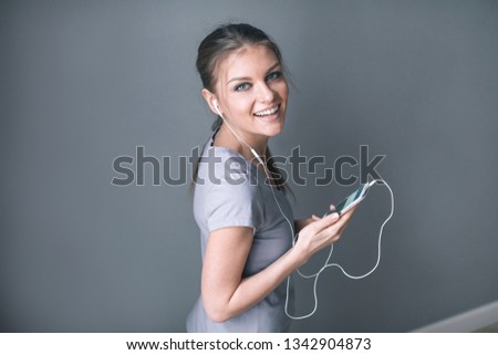 Happy pretty woman in earphones listening to music and holding mobile phone. Lifestyle