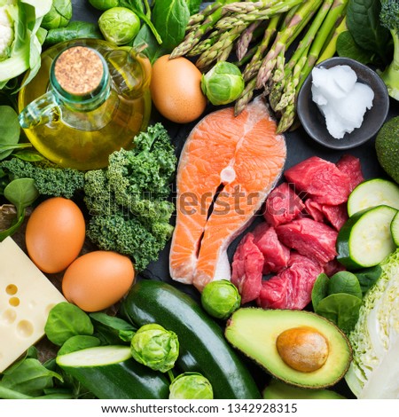 Balanced diet nutrition keto concept. Assortment of healthy ketogenic low carb food ingredients for cooking on a kitchen table. Green vegetables, meat, salmon, cheese, eggs. Top view background