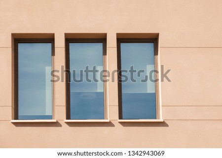 The windows on the light wall. Three windows. Conciseness. Conceptual photo. Urbanization. City architecture.