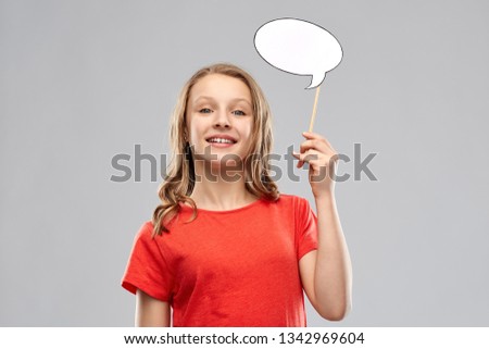communication and people concept - smiling teenage girl with long hair in red t-shirt holding blank speech bubble over grey background