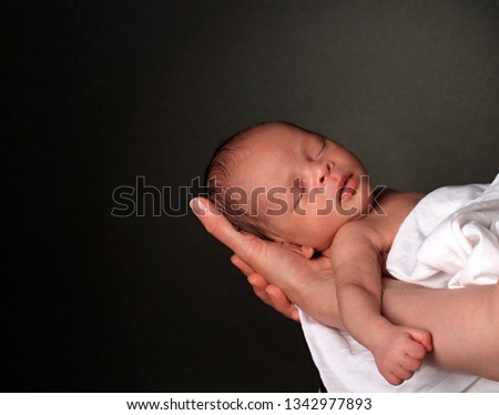 baby in mother's arms and wrapped up in white blanket just been cared for after having a good sleep in bed stock photograph stock photo