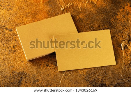 Mockup of golden foil blank business cards stack and single business card at textured yellow luxury background.