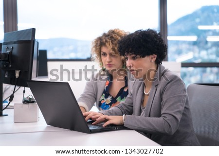 group of young female software developers using laptop computer while writing programming code at modern creative startup office