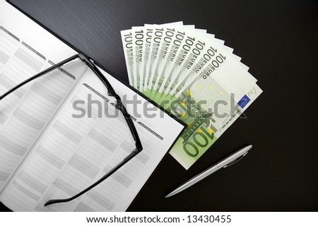 One thousand euro on office table whit organizer, glasses and pen