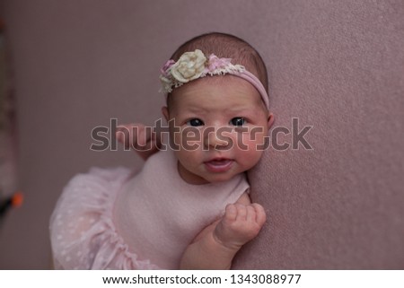 Portrait of newborn baby girl. She is in beautiful handmade pink dress and headband. 