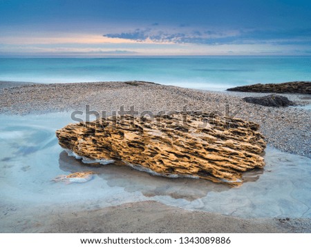 landscape with golden stone in water on the beach before sunset