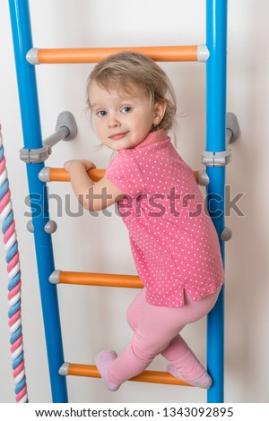 Little happy girl climbing the ladder - home sport activity concept